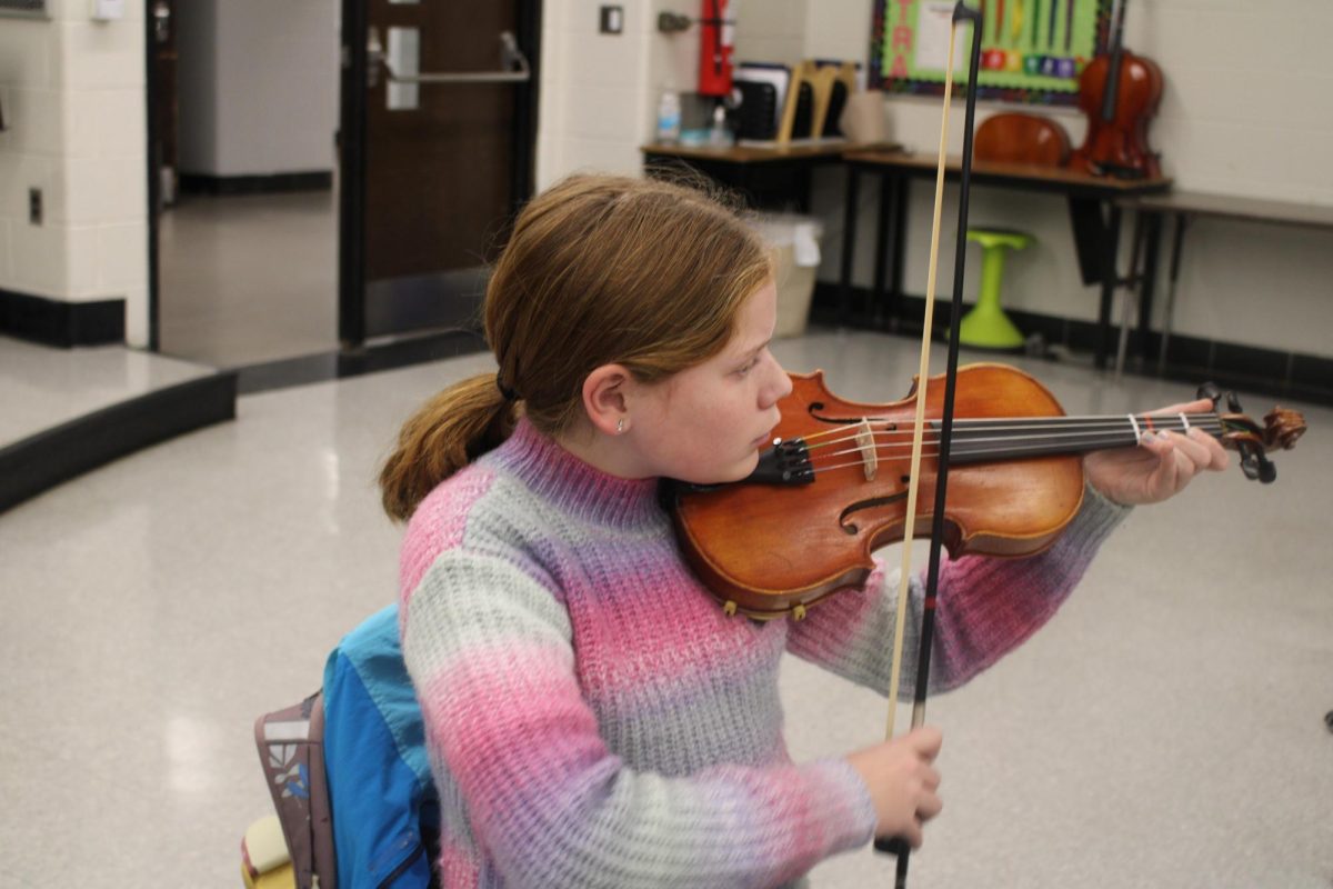 Sixth grader Elsie McCracken playing a string instrument during orchestra practice club.