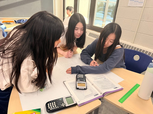 Angela Oh, Elyse Kwon, and Violet Kang working on making a poster in math class.