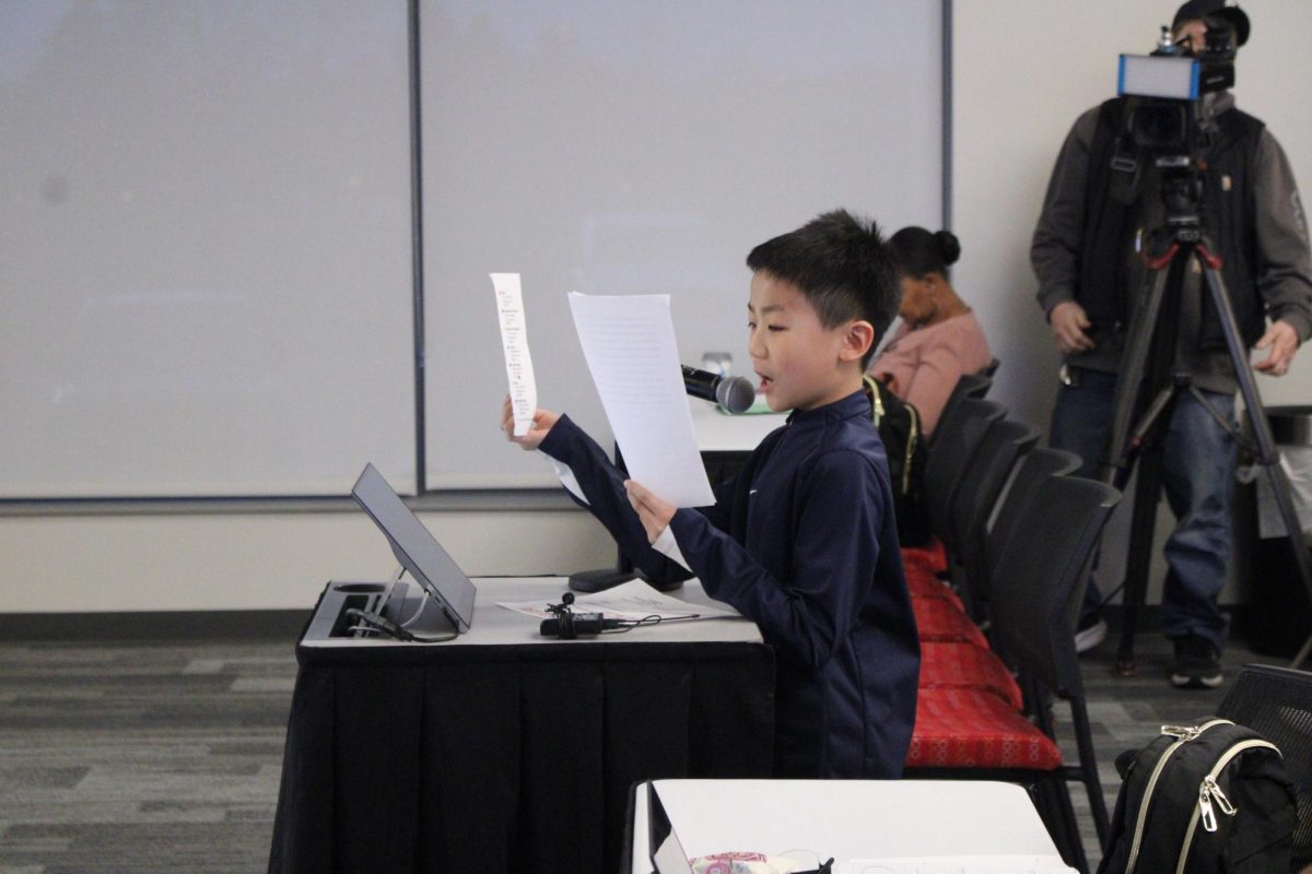 A Thurston fifth grade student holds up graphs and talks about how great Ann Arbor teachers are. Within his research he cited how many teachers switch into different districts for more money.
